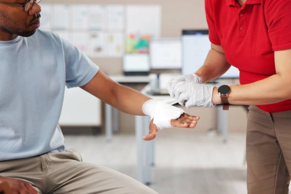 Hands, people and first aid with bandage, teaching or tutorial with care