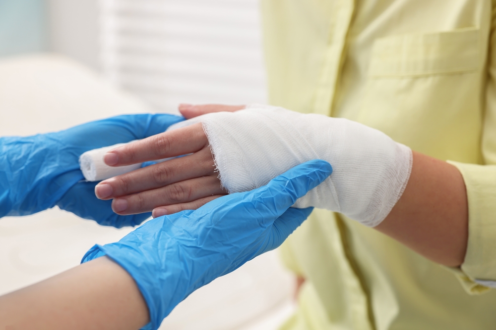 Doctor bandaging patient's burned hand indoors